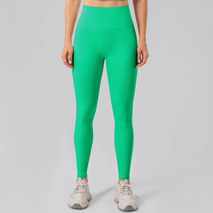 Woman wearing bright green yoga leggings and sneakers on a gray background.